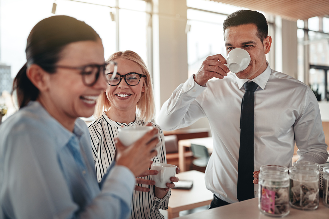 Young businesspeople laughing together during their office coffee break